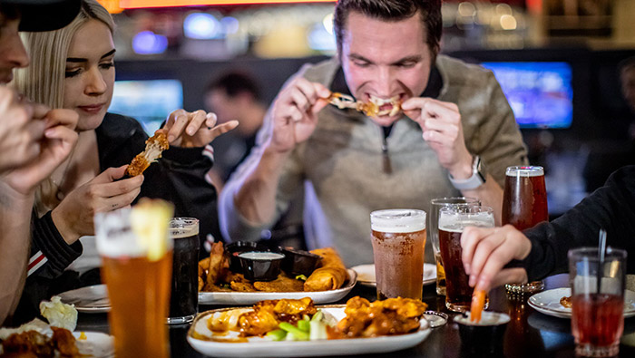 group of people eating wings and drinking beer